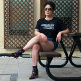 Liz Tran sitting on a bench wearing a black crop top with 'Eccentric Auntie' text in size large from The Iris Collection by Alexandria Boddie and Liz Tran.
